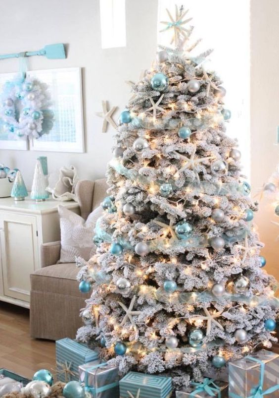 a gorgeous flocked coastal Christmas tree with blue and pearly ornaments plus lights and star fish