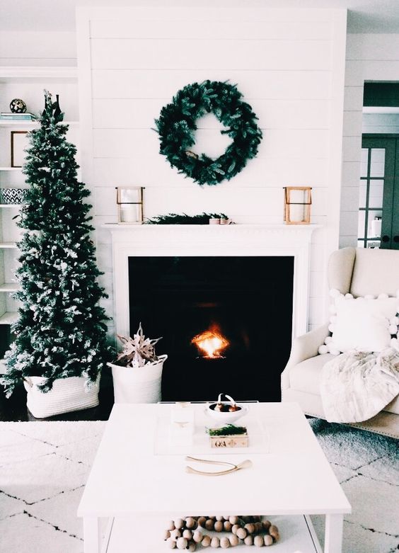 a neutral living room decorated with evergreens - a wreath and a plain Christmas tree for a laconic look