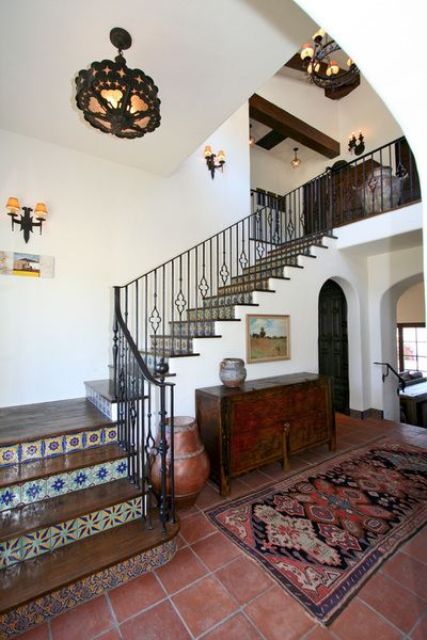 colorful mosaic tiles on the stairs and a bright print rug plus a vintage dresser for a Mediterranean entryway