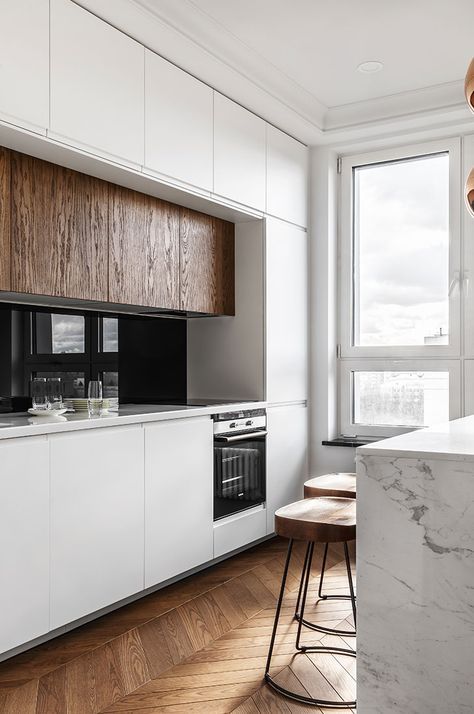 A minimalist kitchen done in white, with a marble kitchen island and rich colored wooden cabinets
