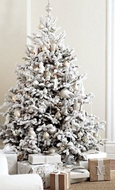 a snowy Christmas tree with pearly and silver ornaments, snowy branches and a silver topper