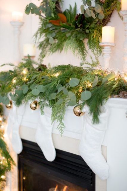 an evergreen wreath and a matching garland with lights and gold Christmas ornaments hanging down