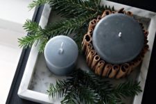 10 candles in soft grey covered with cinnamon sticks and displayed with evergreens are veyr hygge like