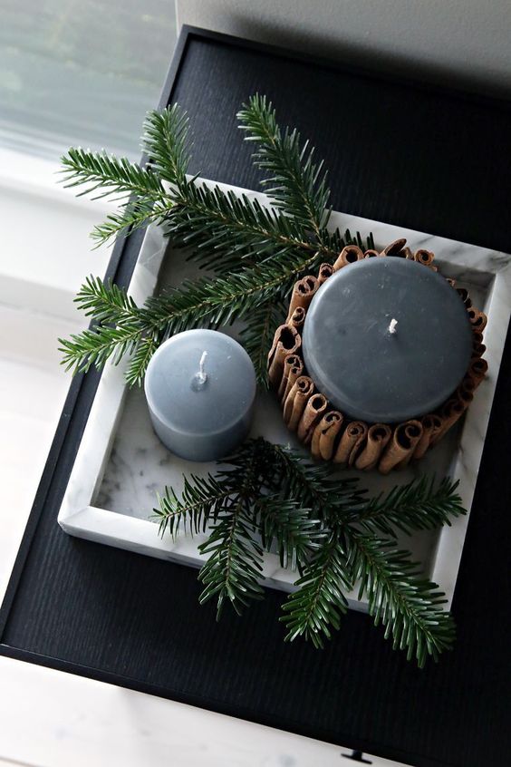 candles in soft grey covered with cinnamon sticks and displayed with evergreens are veyr hygge like