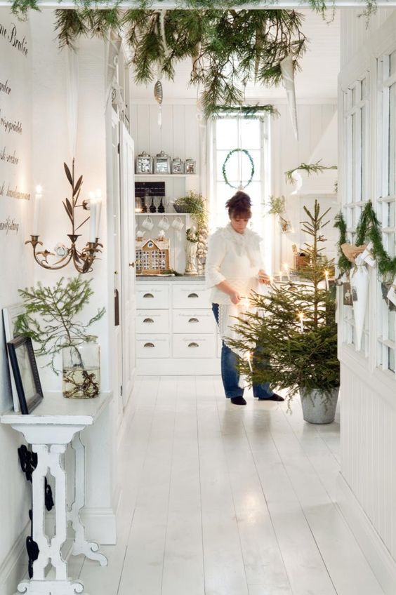 a pure white Christmas home decorated with only evergreens and lights to keep the color scheme matching