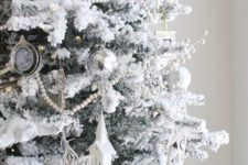 11 a snowy Christmas tree with star,church and snowflake ornaments and bead garlands looks like a frosted one