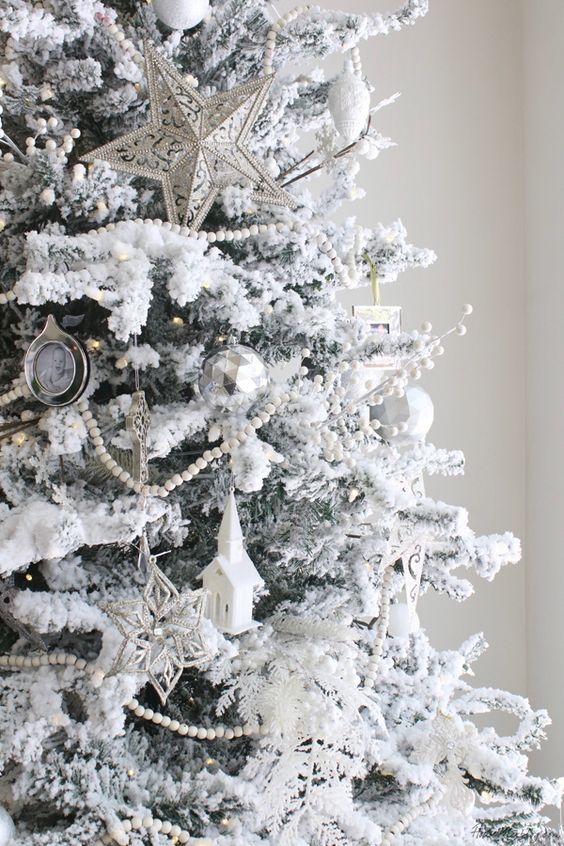 a snowy Christmas tree with star,church and snowflake ornaments and bead garlands looks like a frosted one