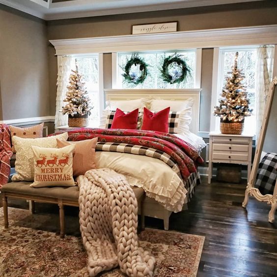 a traditional Christmas bedroom with plaids, chunky knit, flocked trees and evergreen wreaths over the headboard