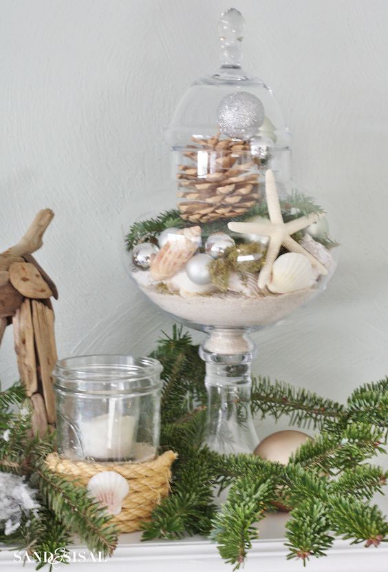 a beach Christmas display of a jar with sand, seashells, star fish, a pinecone and evergreens is a chic idea