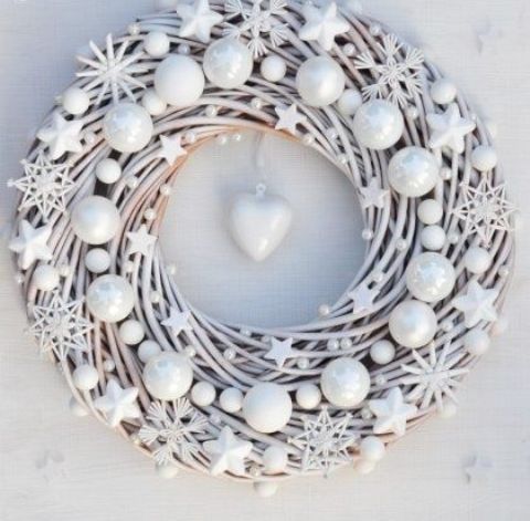 a beautiful white Christmas wreath decorated with stars, snowflakes and beads with a heart in the center