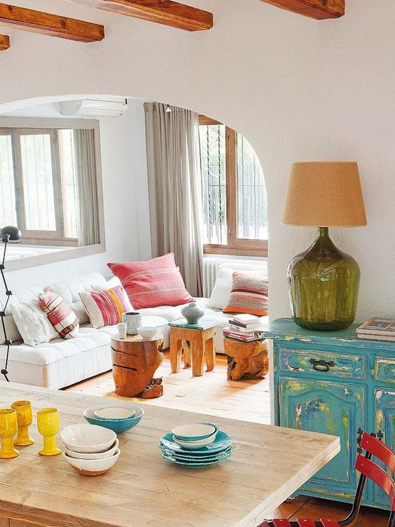 a bright turquoise shabby chic sideboard, some wood carved stools and colorful textiles make up the space