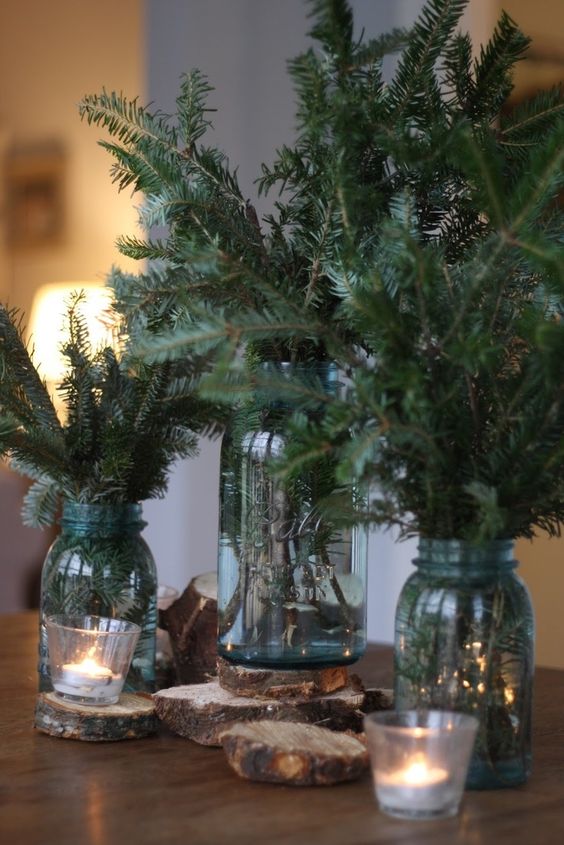 a trio of mason jars with evergreens, candles and wood slices ccan be used as a display or centerpiece