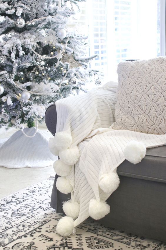 a beautiful white throw with pompoms and a knit pillow is a cool idea for a cozy Christmas nook