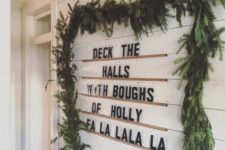 15 a sign made using ledges on the wall and a lush evergreen garland covering them for modern vibes