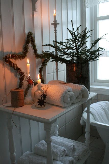evergreens and moss enliven this neutral Nordic bathroom and candles create a mood