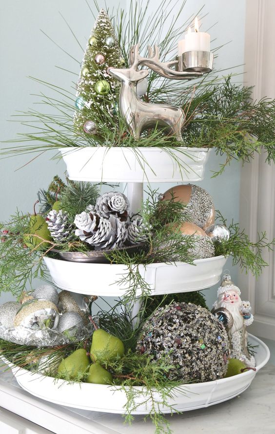 a cupcake stand done in silver and greens, with evergreens, snowy pinecones, deer and Santa figurines and pears
