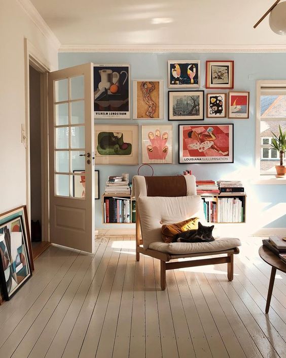 an eclectic living room with a gallery wall of colorful artworks that make up the centerpiece of the room