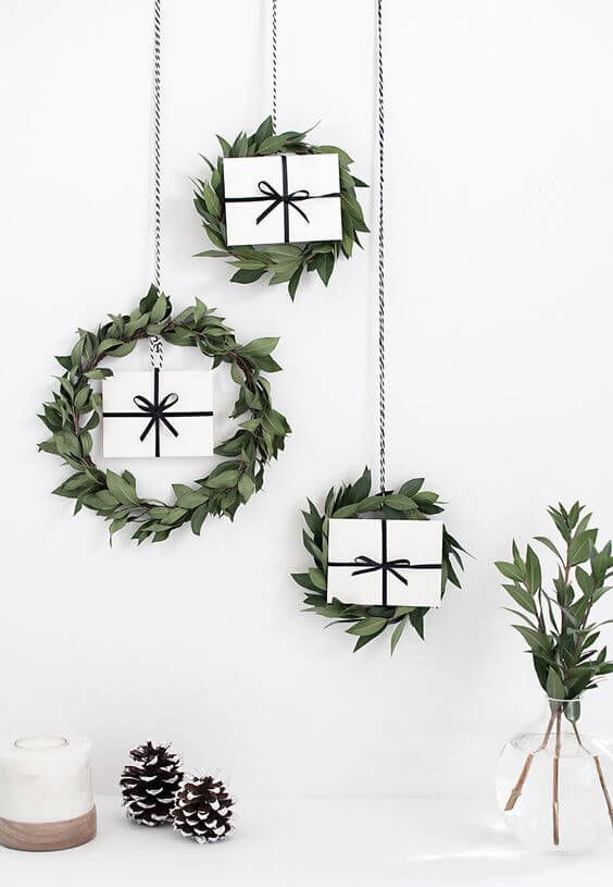 a trio of greenery hanging wreaths with gifts for a Scandinavian or minimalist space