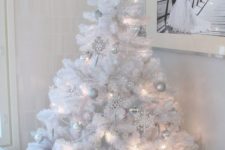 18 a pure white Christmas tree with lights and silver and white ornaments plus a star on top