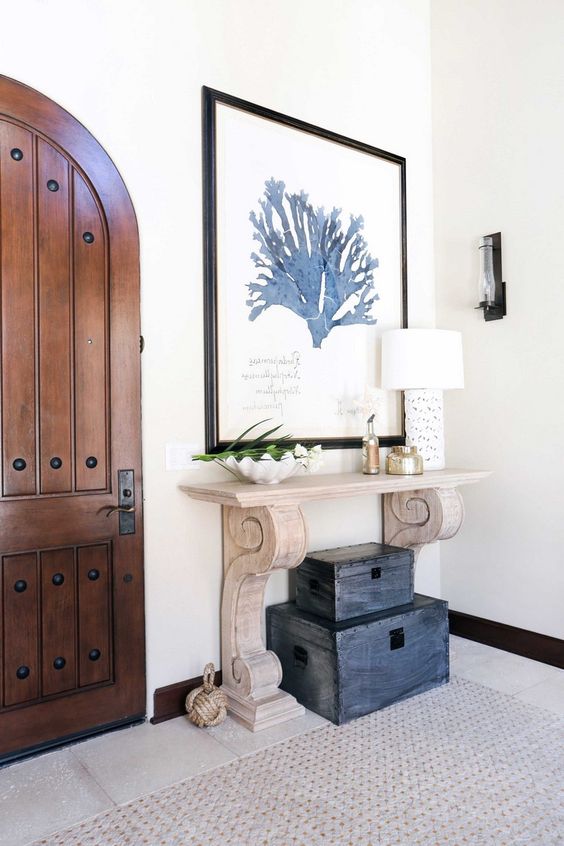 a wood carved console and a stack of vintage chests make the entryway really beachy and Mediterranean