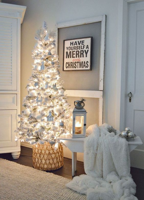 a neutral space is accented with a white Christmas tree with lights, ornaments and faux fur for a charming feel