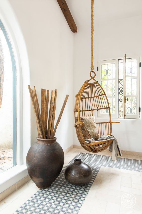 a suspended wicker chair hanging inside will make it feel outside and some dark ceramics and mosaic tiles help creating an ambience
