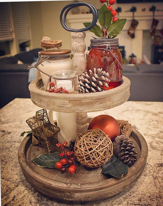 a two-tiered Christmas tray with fake berries, pinecones, a twine ball and beautiful candles
