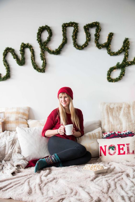 an evergreen and lights letter Christmas garland attached to the wall for a holiday mood