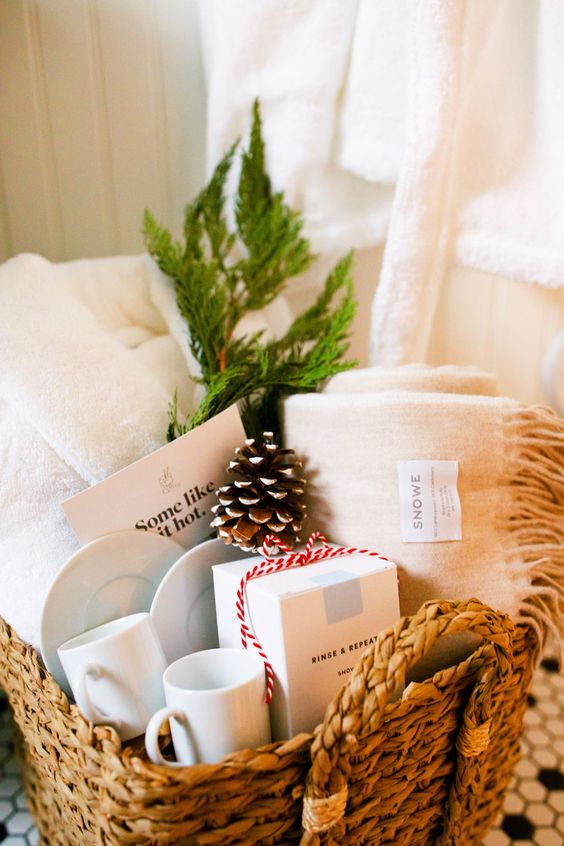a basket with towels, a snowy pinecones, mugs and evergreens is ideal to take a luxurious bath at Christmas