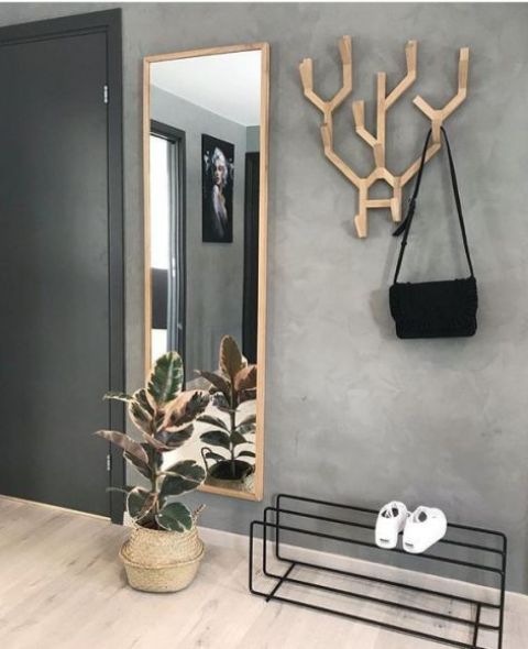 a creative wooden antler coat rack and a mirror in a wooden frame make an accent in a minimalist entryway
