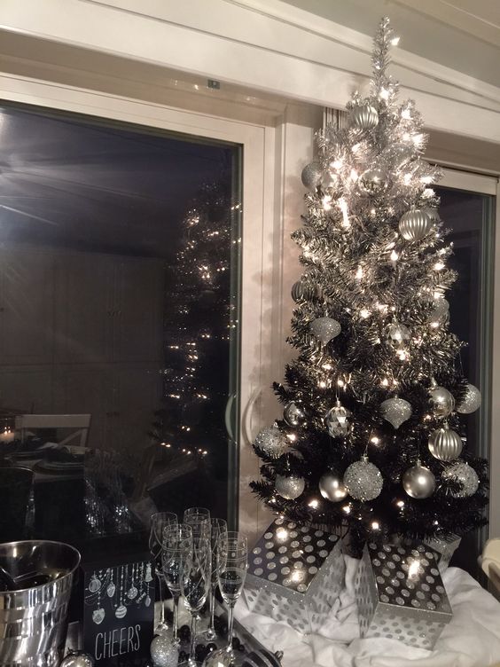 a cute tabletop ombre silver to black tree is styled with glitter and shiny silver ornaments and lights