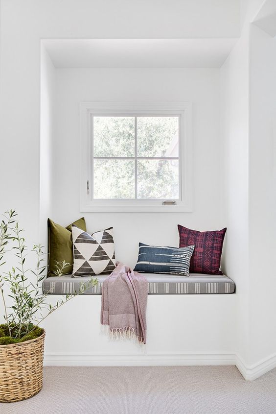 a white space with colorful textiles with prints that make this windowsill bench brighter and catchier