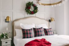 22 a traditional Christmas bedroom with an evergreen and red bloom wreath, plaid pillows and a red blanket