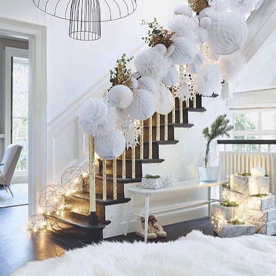 a white hallway with a faux fur rug, white paper ornaments attached to the railing and lots of light lining up the stairs