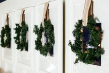 22 family photos hanging on the wall are covered with greenery wreaths and ribbons for a festive feel