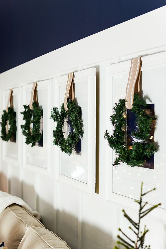 family photos hanging on the wall are covered with greenery wreaths and ribbons for a festive feel
