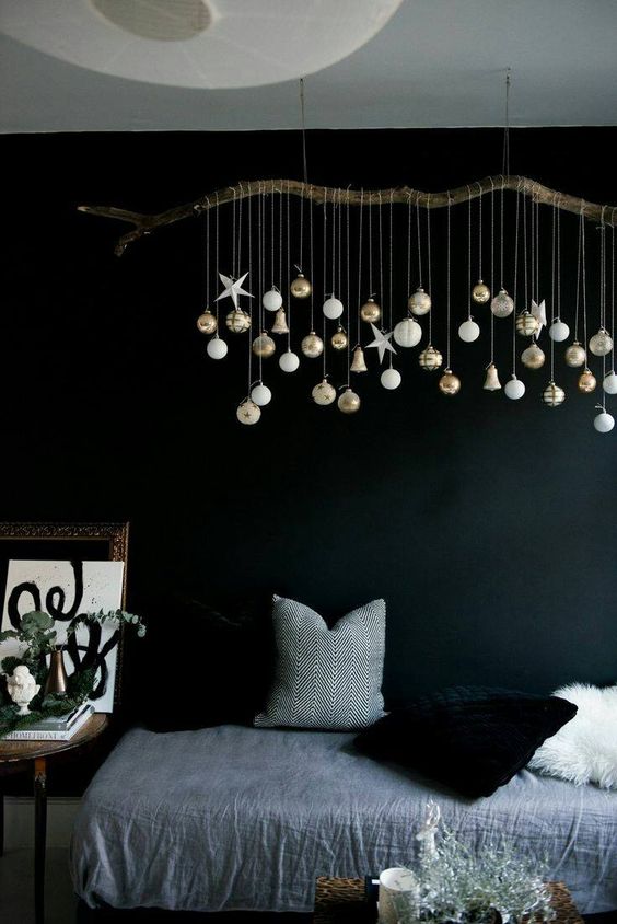a branch with hanging down Christmas ornaments is a cool idea to decorate any space with modern vibes