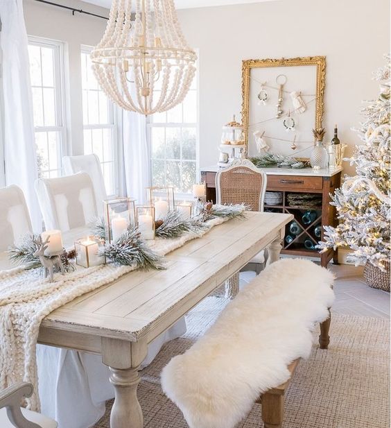 a white table setting with a knit throw, a faux fur throw on the bench and snowy evergreens