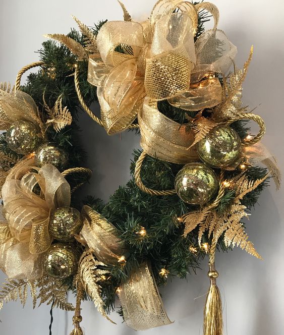 a lush and holiday Christmas wreath decorated with gold bows, tassels and ornaments