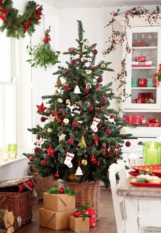 A cute Scandi inspired Christmas tree in a basket with red ornaments and stockings plus gifts for coziness