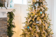 a Christmas tree done with metlalic and blue ornaments and burlap ribbons that give a rustic feel