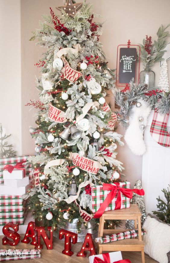 a classic Christmas tree with white ornaments, red berries, fabric blooms, bells and Merry Christmas ribbons all over