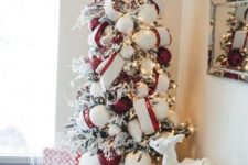 a cute and cozy flocked Christmas tree decorated with oversized white and red ornaments plus red and white ribbons
