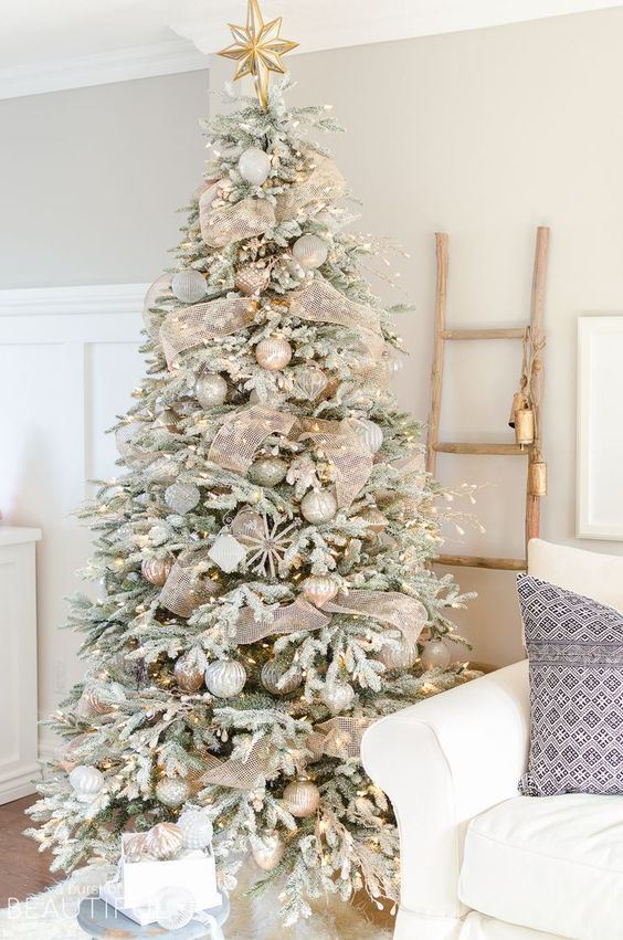 a snowy Christmas tree with lights, metallic ornaments and sheer gold ribbon plus a star on top