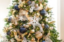 bold Christmas decor with oversized navy and gold ornaments, lights, snowflakes and gold and white ribbons for decor