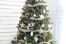 rustic chic Christmas tree decor with wooden and white ornaments and burlap ribbons going horizontally with a star on top