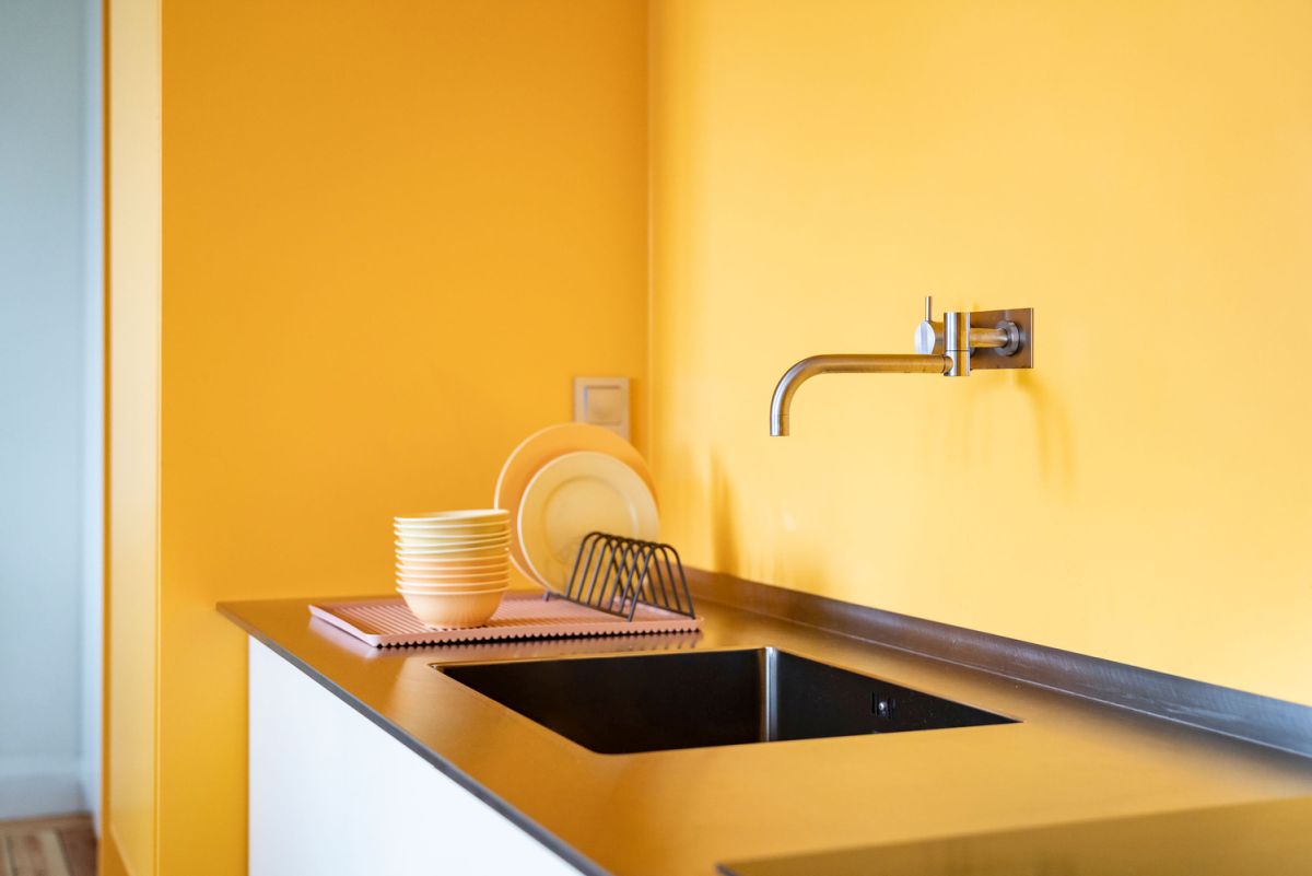 The warm yellow tone of the walls is reflected into the kitchen counter, adding a comfortable vibe to the decor