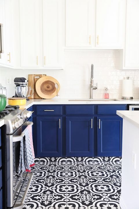 a chic and bold kitchen with navy cabinets and white countertops and mosaic navy and white tiles on the floor