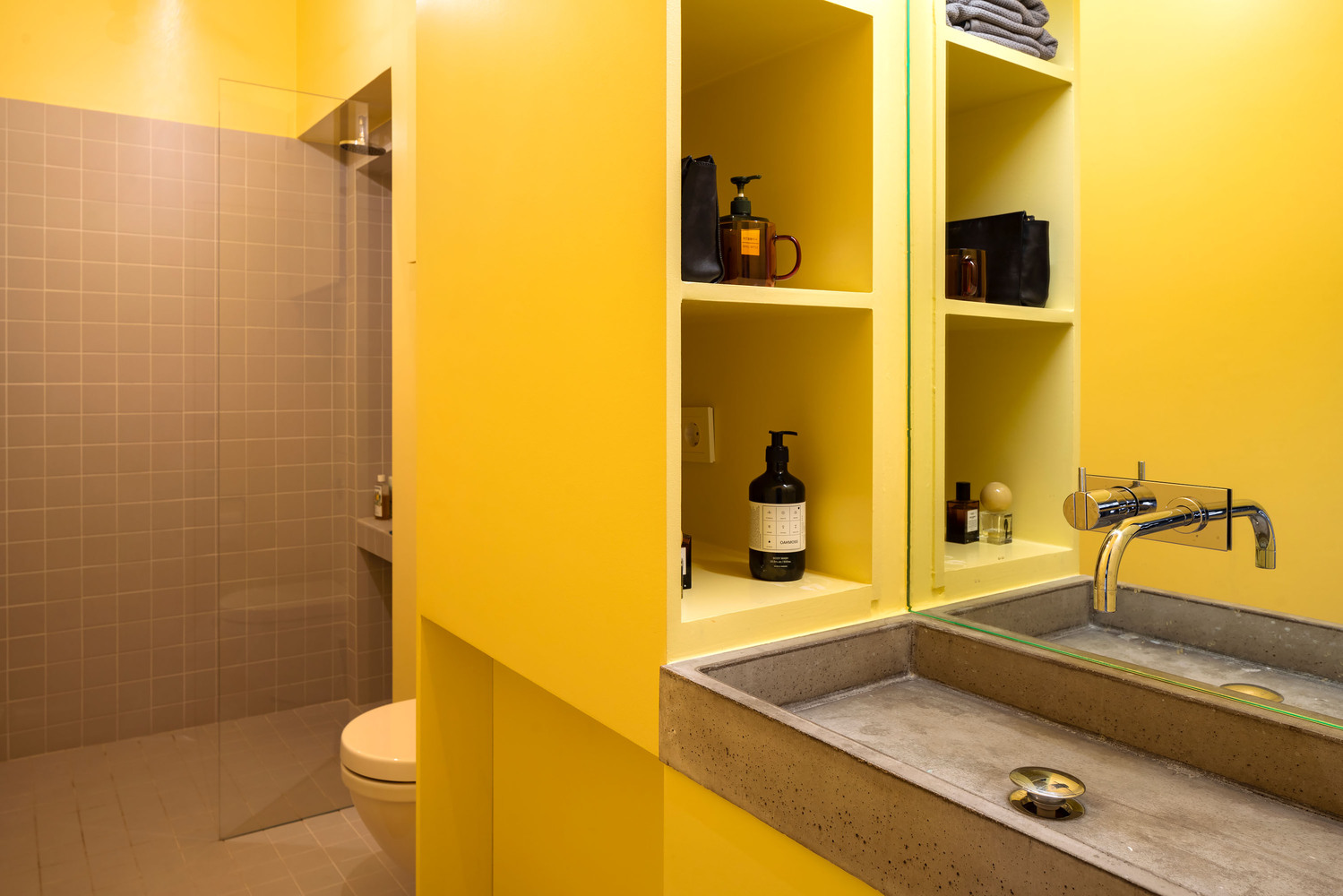 The bathroom combines yellow and greys - grey tiles and a concrete sink