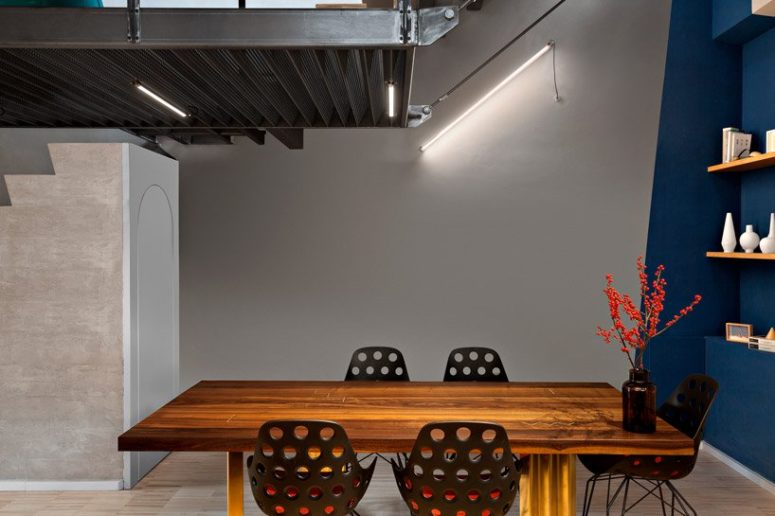 The dining space features geometric decor, industrial lighting, a bold dining table and metal perforated chairs